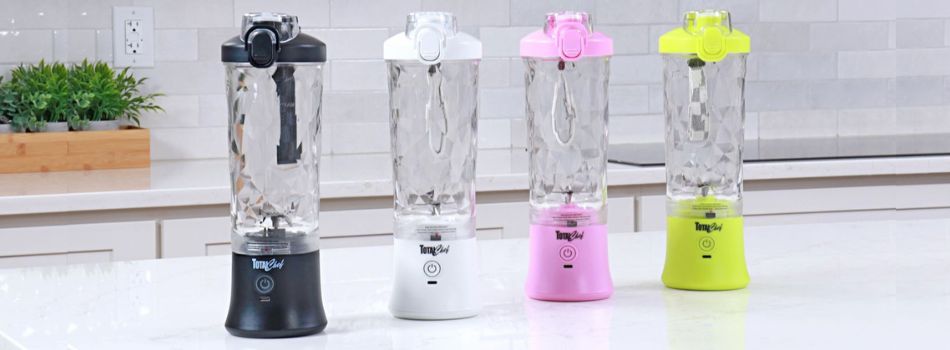 Four different coloured Total Chef portable cordless rechargeable blenders in a row in a white kitchen