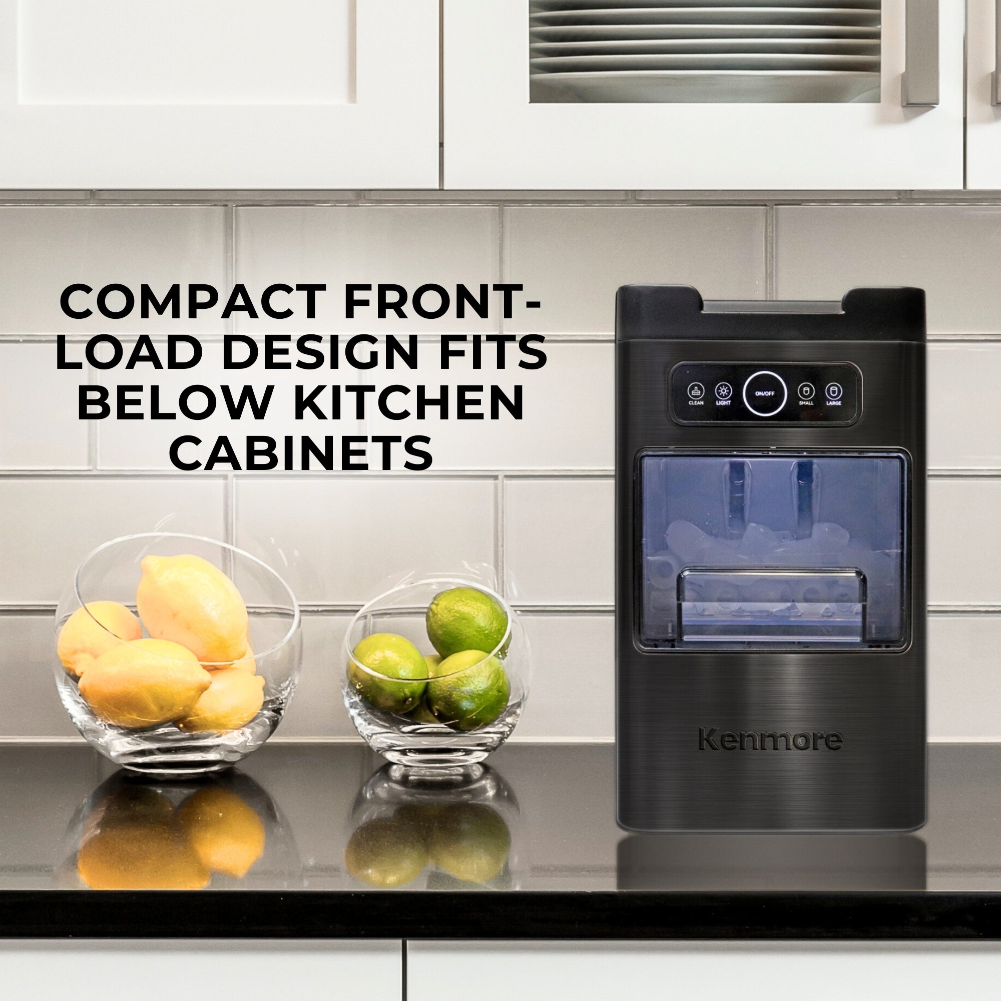 Kenmore space-saving front-load ice machine and glass bowls of lemons and limes on a black kitchen counter with a white tile backsplash and white cabinets above and below. Text overlay reads, "Compact front-load design fits below kitchen cabinets"