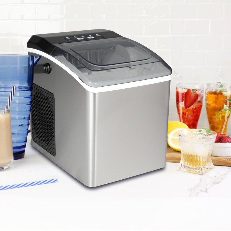 Lifestyle image of ice maker on a white countertop with white tile backsplash behind and glasses of juice, iced tea, water, and iced coffee on either side.